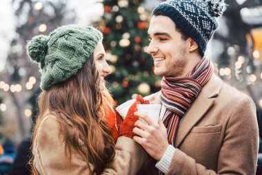 Kadın ve erkek yılbaşı pazarında sıcak şarap içiyor.