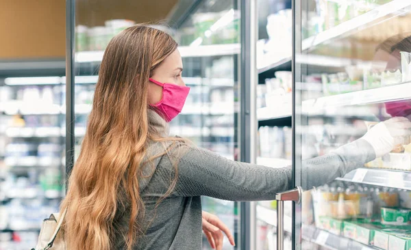 Женщина в супермаркете делает покупки на молочном острове во время изоляции — стоковое фото