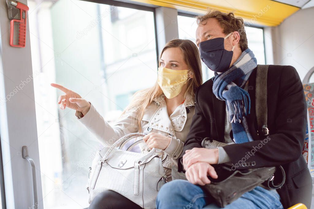 Couple in public transport bus wearing masks