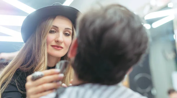 Barber woman trimming beard of client with machine