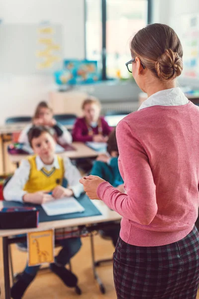 Nauczycielka z uczniami w szkole podstawowej — Zdjęcie stockowe