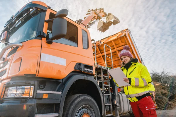 Worker watching a lorry with gripper unloading biomass — Stock Photo, Image