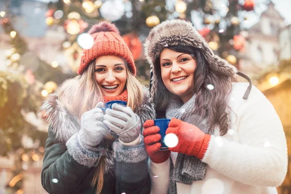 Mejores amigos disfrutando del vino caliente en el mercado de Navidad —  Fotos de Stock