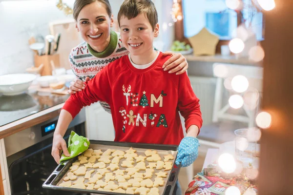 Family baking Christmas cookies in kitchen carrying sheet with dough