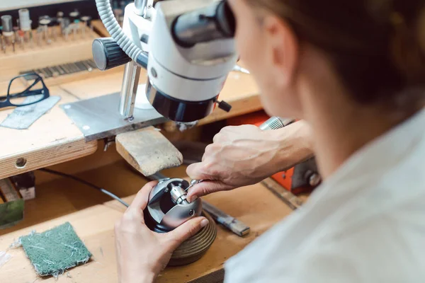 Gioielliere diligente che lavora al microscopio al suo banco da lavoro — Foto Stock