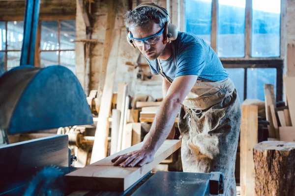 Carpintero trabajando sobre madera con la sierra circular — Foto de Stock