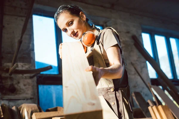 Mulher bonita carpinteiro verificando qualidade de uma prancha — Fotografia de Stock