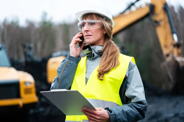 Trabalhador mulher em mineração a céu aberto usando telefone — Fotografia de Stock