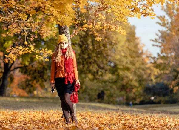 Orolig kvinna kollar sin telefon bär mask i höst — Stockfoto