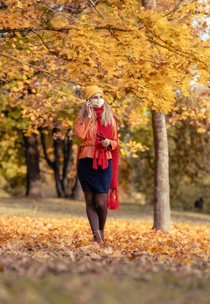 Kvinna som använder sin telefon har gått i falla park under coronavirus kris — Stockfoto