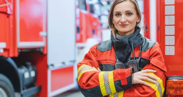 Γυναίκα πυροσβέστης στέκεται μπροστά από ένα πυροσβεστικό όχημα — Φωτογραφία Αρχείου