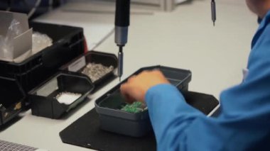 Elektronik üretiminde çalışan bir işçi bir bileşen lehimliyor