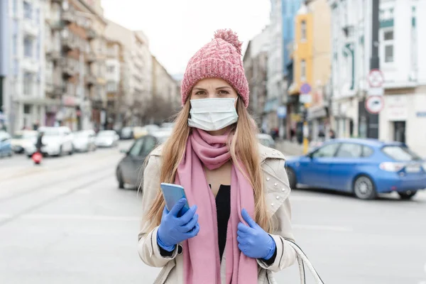 Обеспокоенная женщина, стоящая в изоляторе города в медицинской маске — стоковое фото