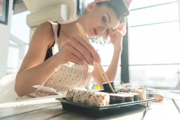 Домохозяйка отдыхает от работы по дому и ест суши. — стоковое фото