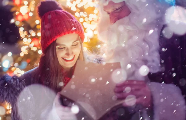 Santa Claus presentando hermosa chica con un regalo —  Fotos de Stock