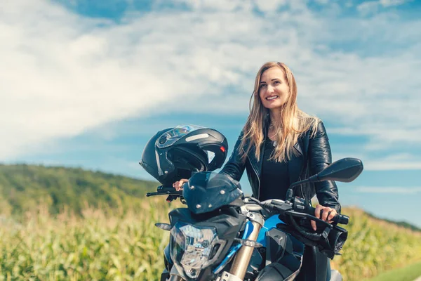 Mulher bonita em uma motocicleta olhando para a estrada à frente — Fotografia de Stock