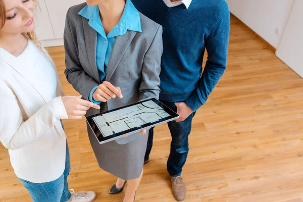 Boende mäklare visar planlösning av lägenhet till kunder — Stockfoto