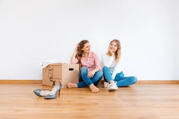Duas mulheres no novo apartamento sonhando com como decorá-lo — Fotografia de Stock