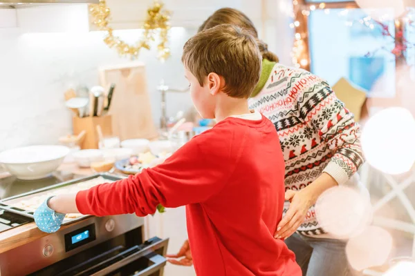 Boy putting sheet with Christmas cooking in the oven — Stock Photo, Image