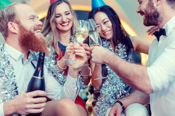 Grupo de amigos em um bar brindar com champanhe e celebrar — Fotografia de Stock