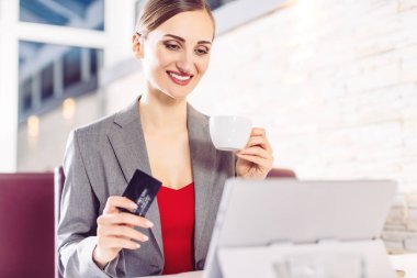 Kafedeki kadın internet sitesinden bir şeyler sipariş ediyor.