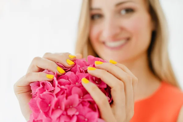 Femmes avec des ongles soignés en jaune tenant une fleur — Photo