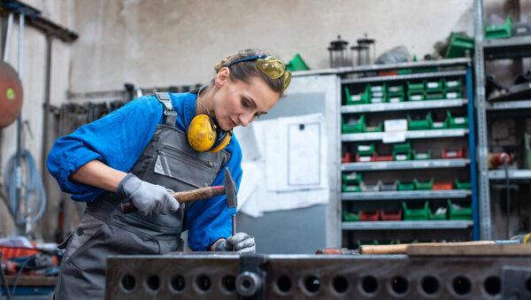 Woman metalworker marking piece of steel