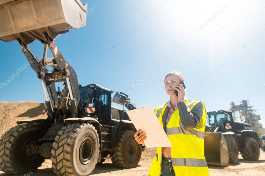 Worker woman with phone and clipboard in mine or quarry