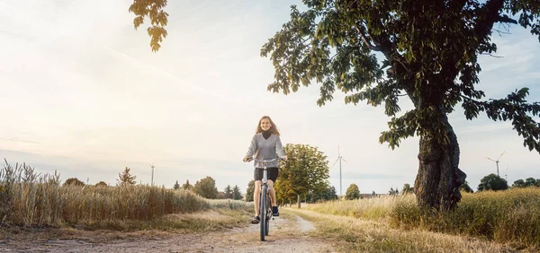 Mulher em uma bicicleta se divertindo na paisagem rural — Fotografia de Stock