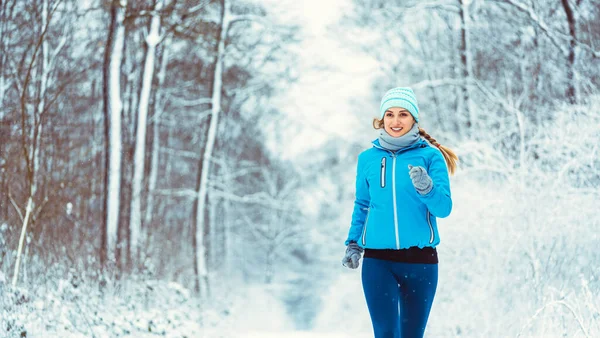 Kobieta jogging w kierunku kamery w zimnym i śnieżnym lesie — Zdjęcie stockowe