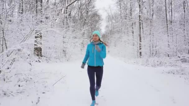 Femme jogging vers la caméra dans la forêt froide et enneigée — Video