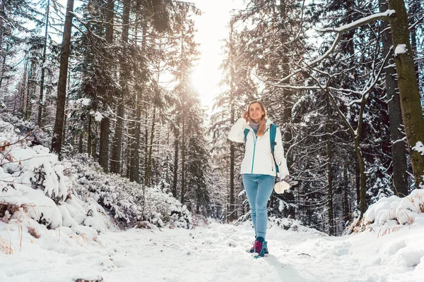 Woman in cold snow hiking down a path thru the woods — Stock Photo, Image