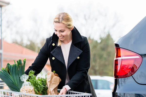 Wanita memuat bahan makanan setelah berbelanja ke bagasi mobilnya — Stok Foto