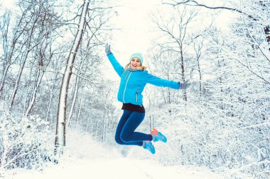Spor elbiseli neşeli kadın kışın ve karın tadını çıkarıyor.