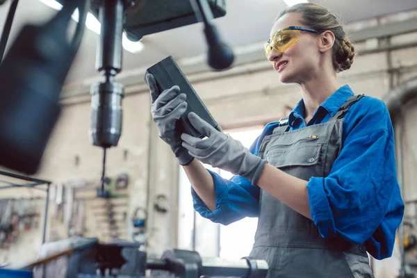 Mulher em oficina de metal verificando peça de trabalho — Fotografia de Stock