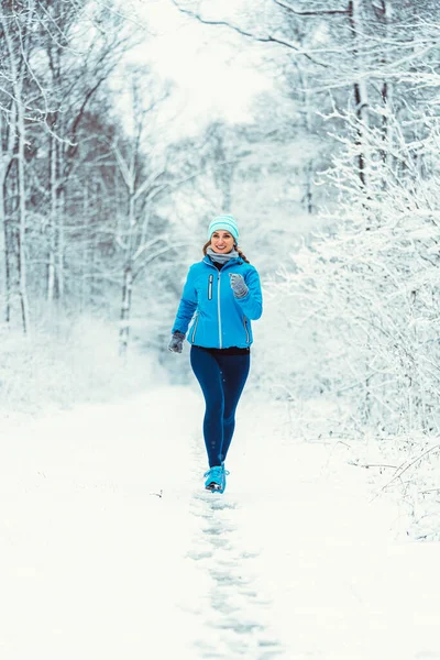 寒さと雪の森の中でカメラに向かってジョギング女性 — ストック写真