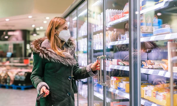 Woman at supermarket freezer section wearing face mask — Stock Photo, Image