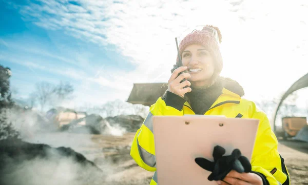 Manager in biomass and landfill operation using her radio in front of machines