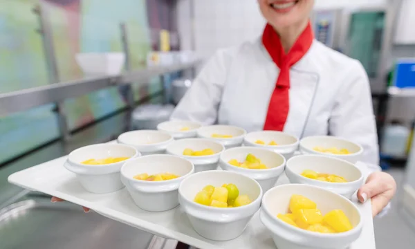 Koch in gewerblicher Küche zeigt Tablett mit Dessert — Stockfoto