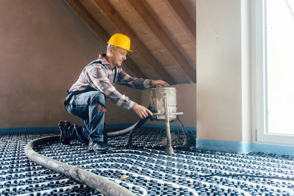 Працівник на будівельному майданчику встановлює труби для теплої підлоги — стокове фото
