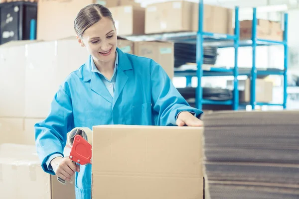 Fabrika deposunda nakliyat için mal paketleyen bir kadın. — Stok fotoğraf