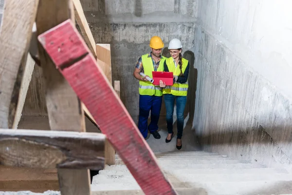 Obrero de la construcción y constructor inspeccionando escaleras en la concha del edificio —  Fotos de Stock