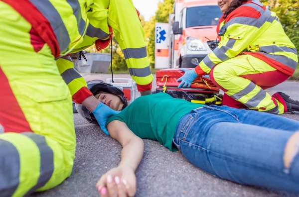 Paramedics removing helmet of injured motorcyclist after an accident — Stock Photo, Image