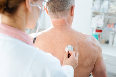 Doktor, insanın akciğer fonksiyonlarını kontrol etmek için stetoskop kullanıyor.