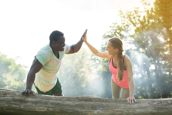 Fitness coach gives some motivation to woman doing push-ups