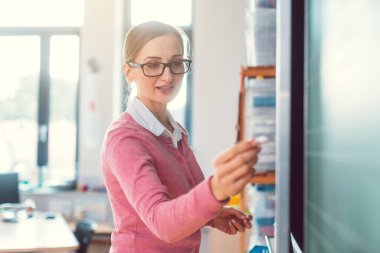 Okulda öğretmen siyah tahtaya bir şeyler yazıyor.