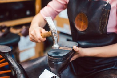 Ayakkabı tamircisi bir kadının ayakkabılarını tamir ederken yakın plan çekimi.