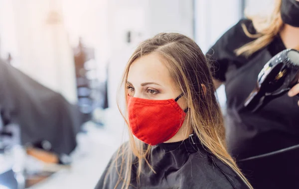 Woman wearing red face mask getting fresh styling at a hairdresser — Stockfoto