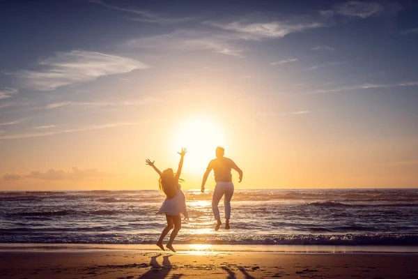 Couple on honeymoon during sunset on the beach jumping high — Foto de Stock