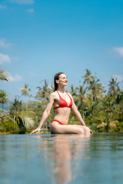 Nő a trópusi nyaralás ül a víz a medence — Stock Fotó